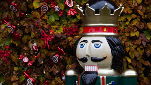 Nutcracker statue in front of hedge decorated for Christmas